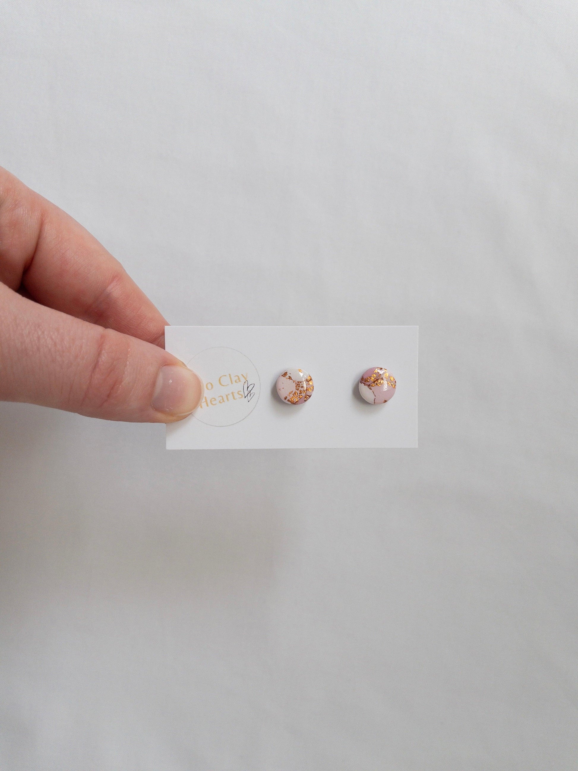 Mini pink and gold circle stud earrings on white ba