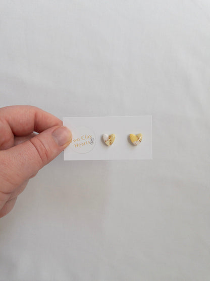 Mini yellow and gold heart stud earrings on white card