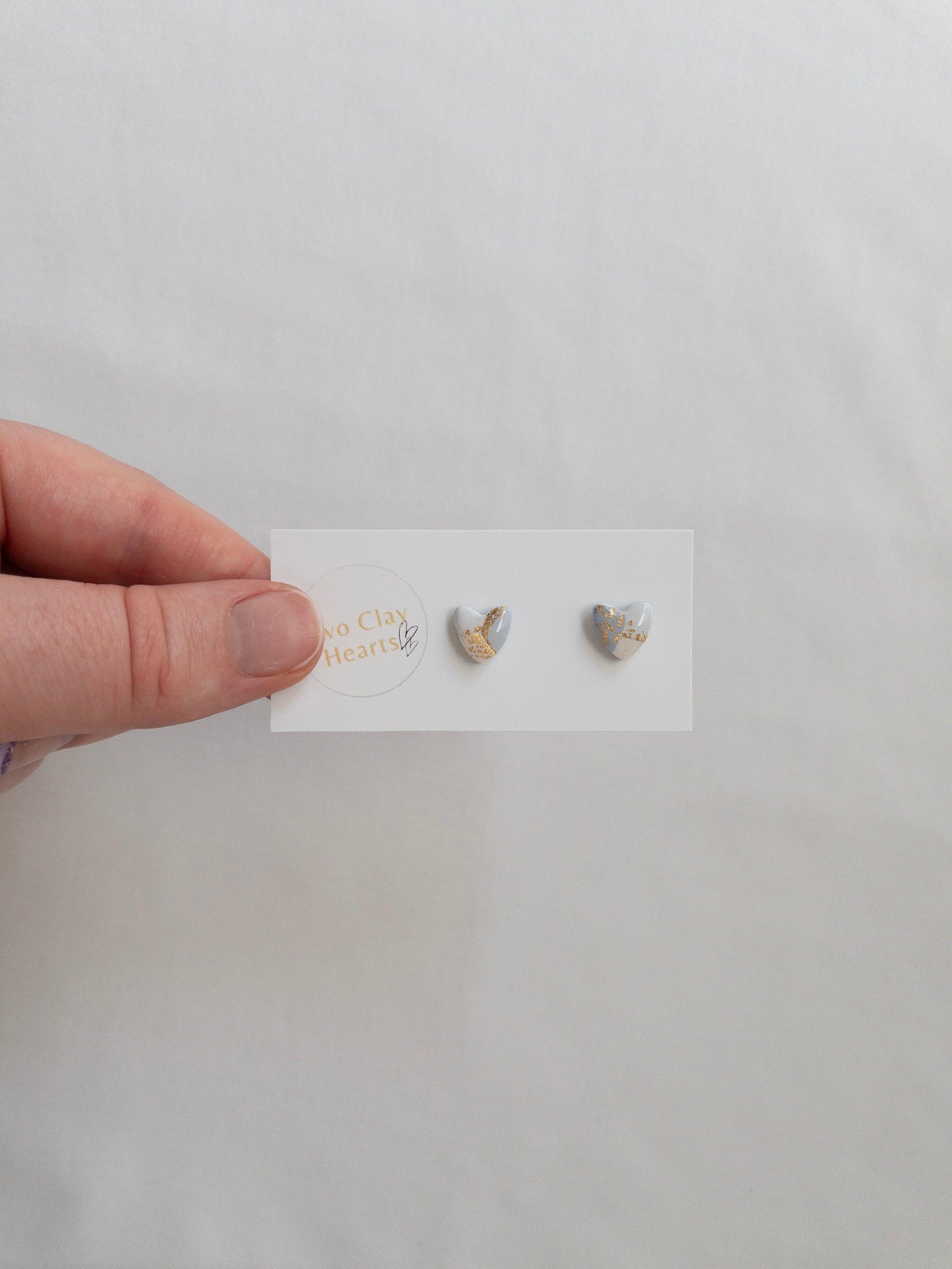 Mini blue and gold heart stud earrings on white card