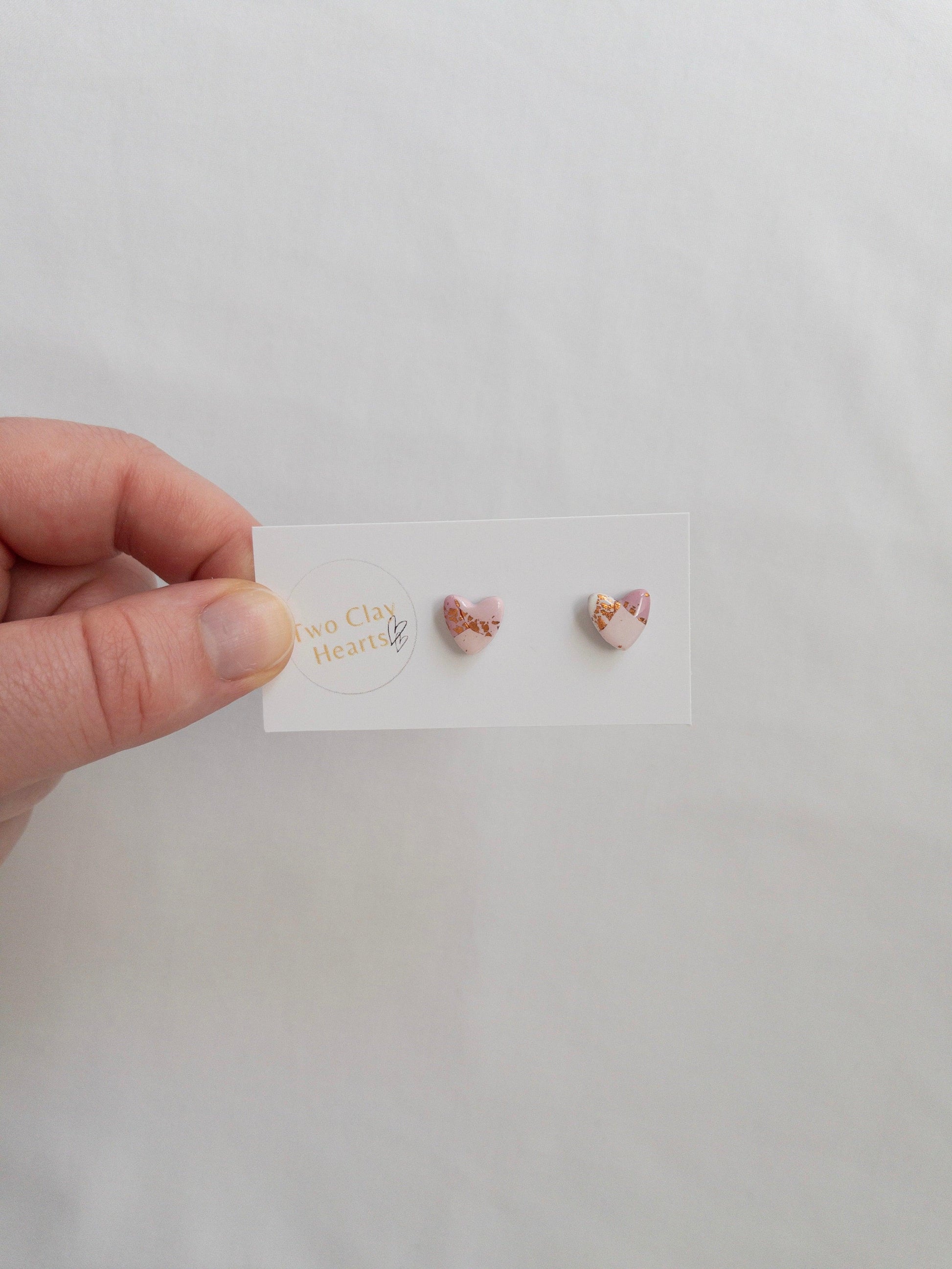 Mini pink and rose gold heart stud earrings on white card