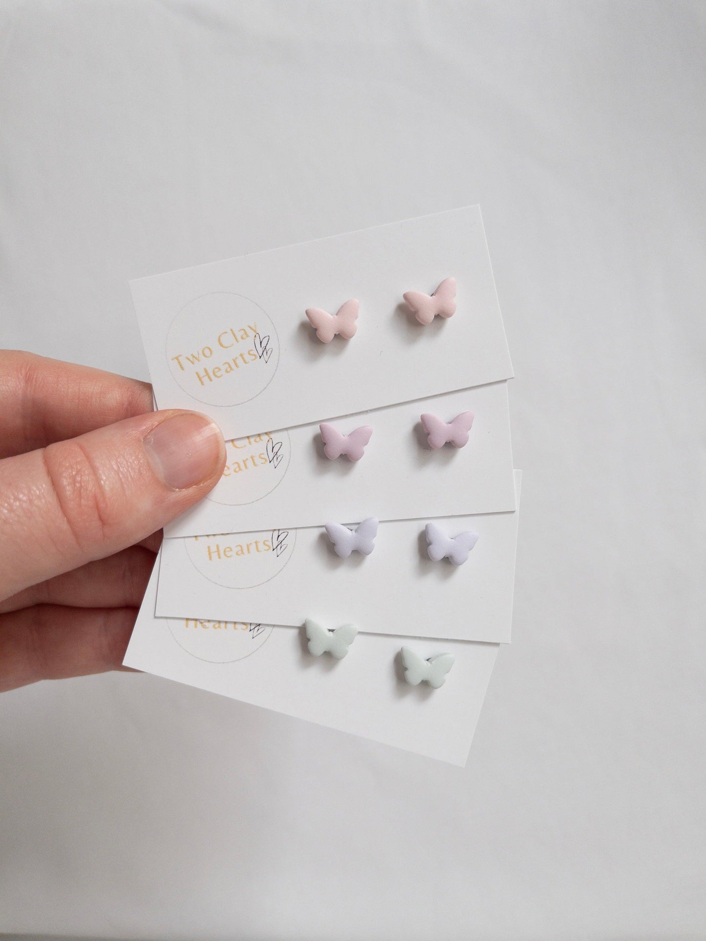 four pairs of tiny pastel  butterfly earrings each in a different colour.