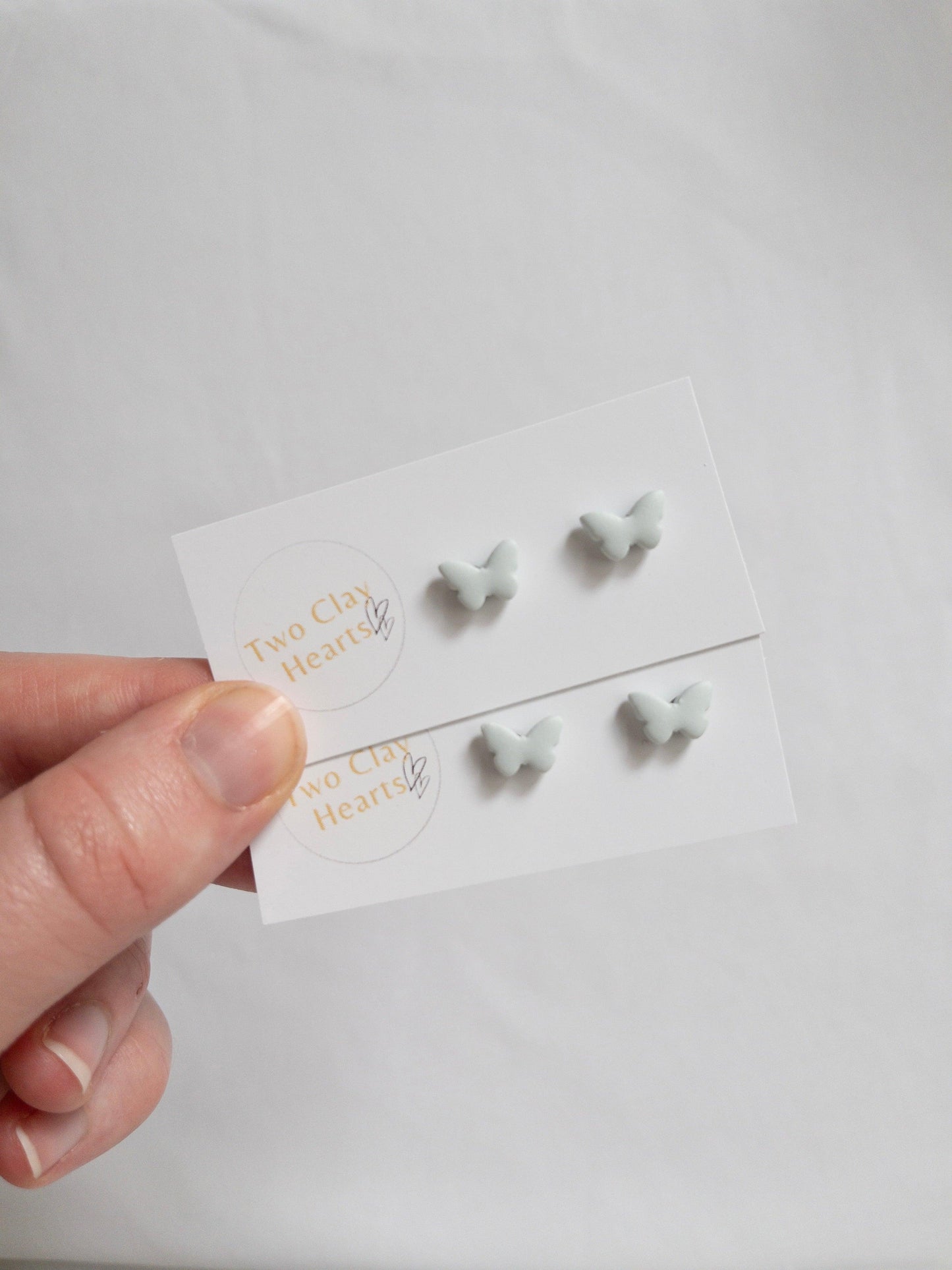 Pairs of tiny pastel green butterfly earrings.