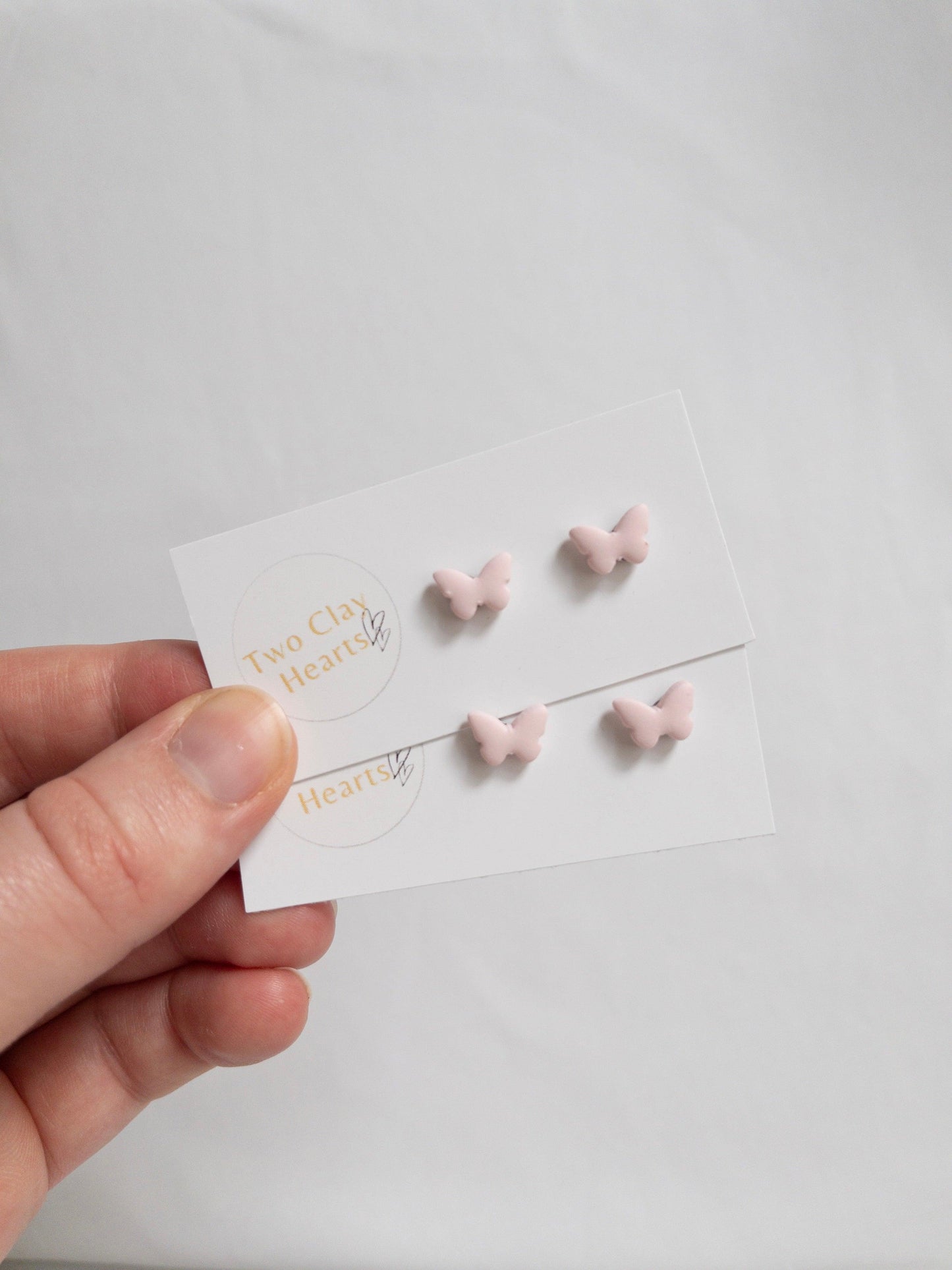 Pairs of tiny pastel pink butterfly earrings.