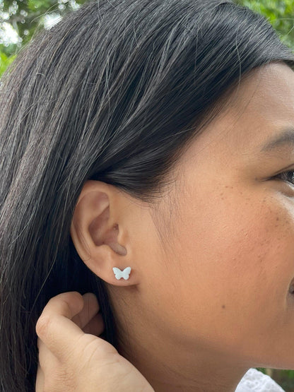 Mini butterfly earrings on an adult models ear