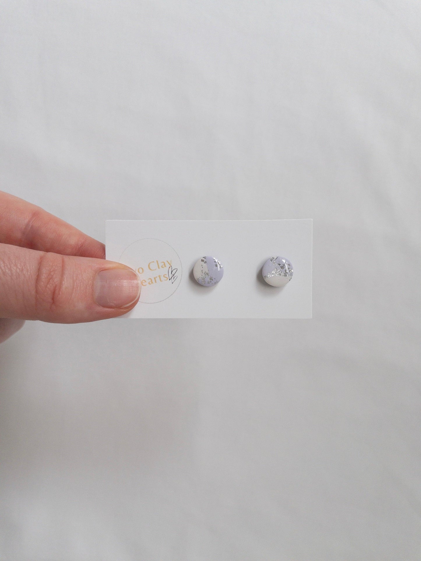 Mini purple and silver circle stud earrings on white backing card