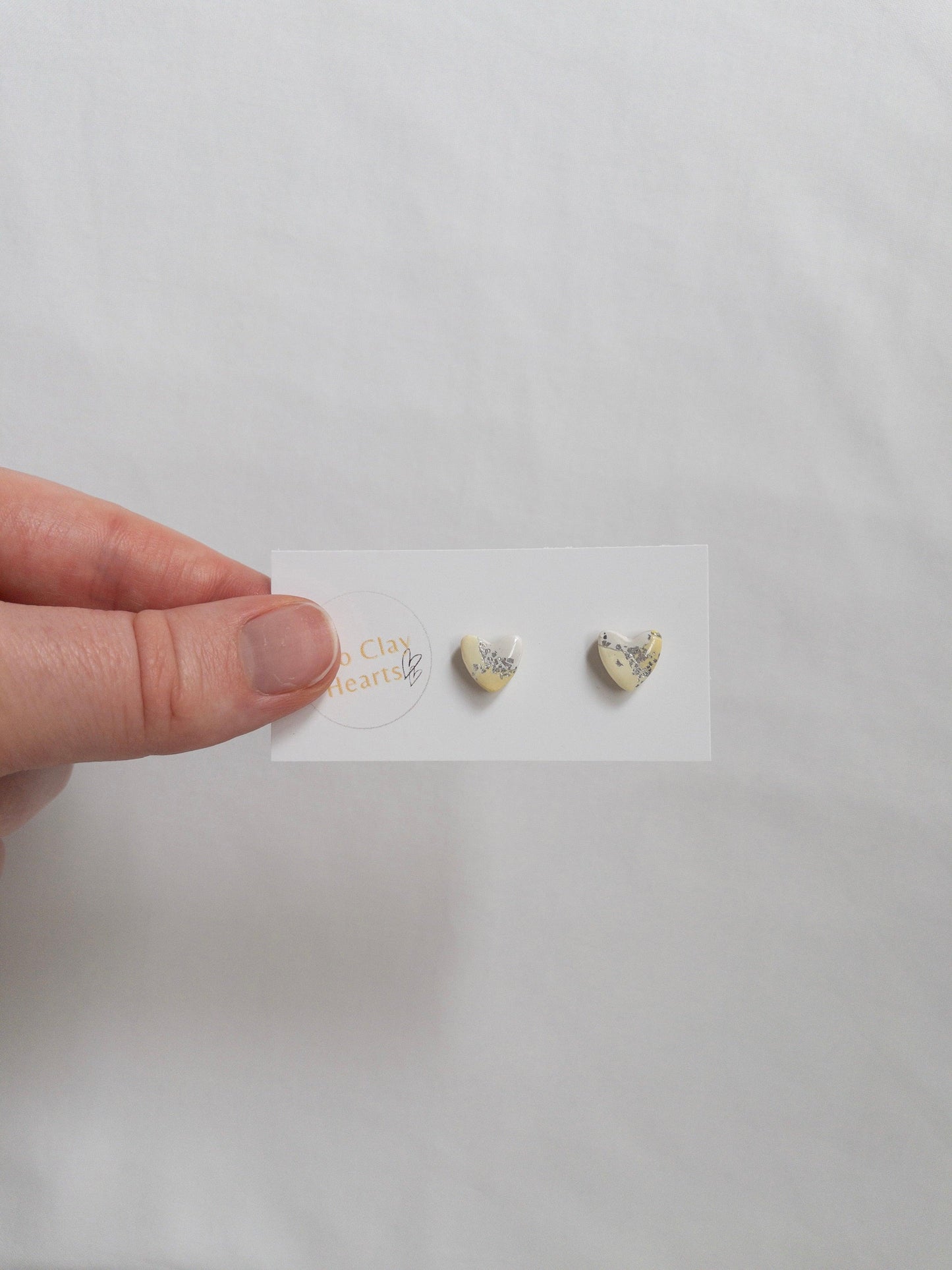 Mini yellow and silver heart stud earrings on white card