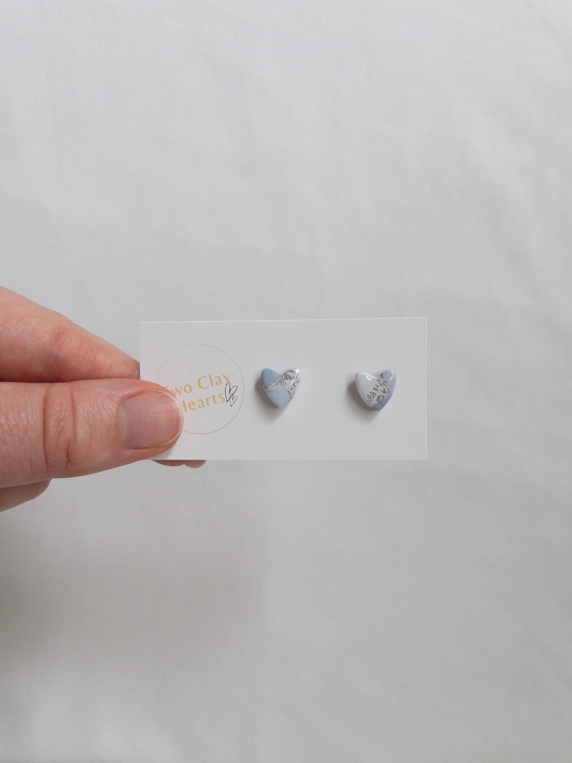 Mini blue and silver heart stud earrings on white card