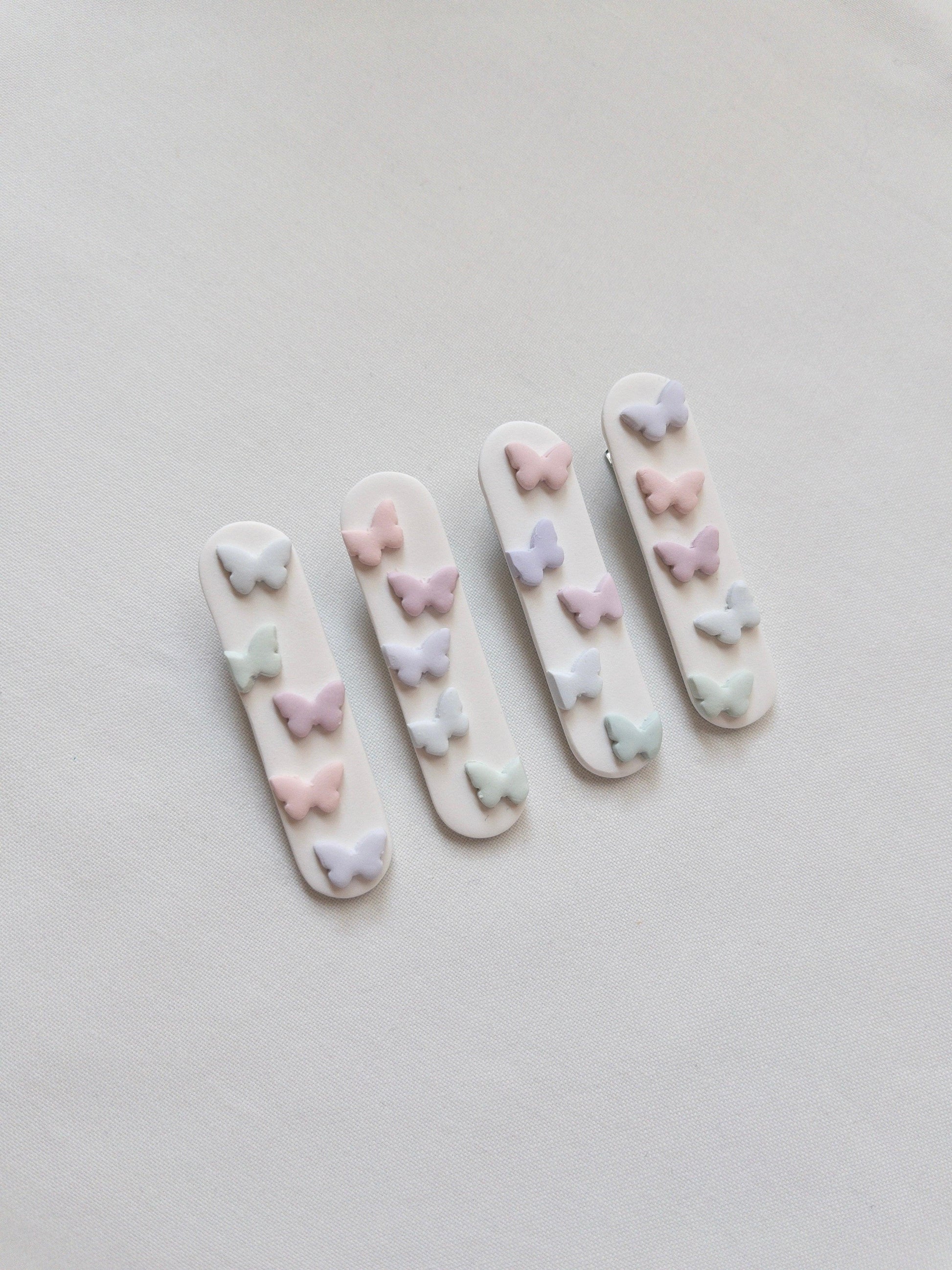 a range of white polymer clay hair clips with pastel butterfly accents on top