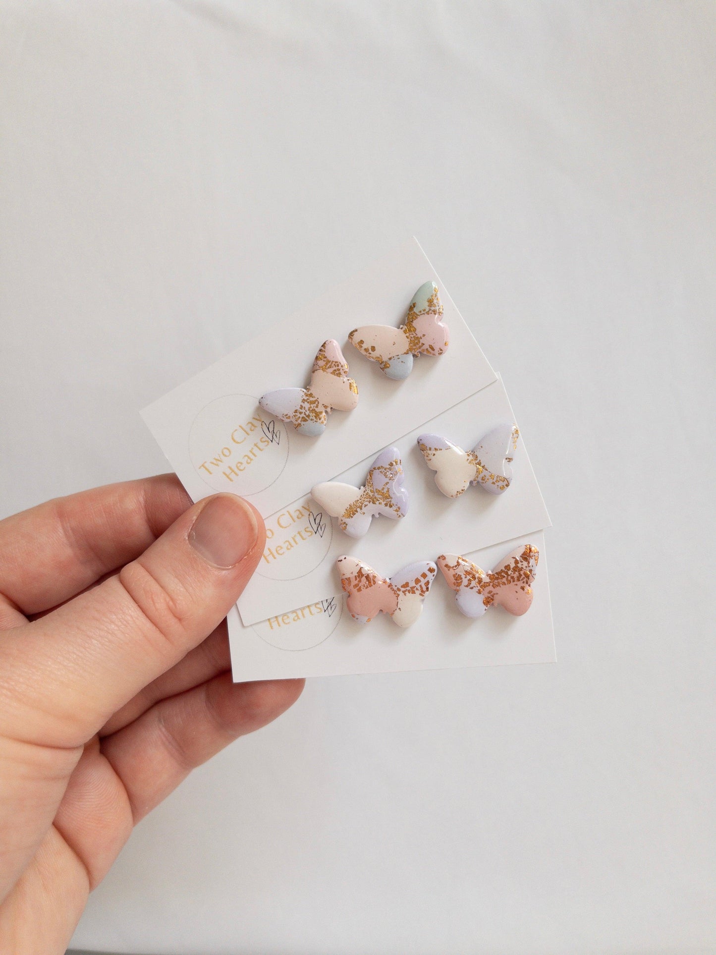 three pairs of butterfly earrings with gold specks, each in a different colour scheme