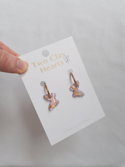 Shiny pink, purple and rose gold hoop earrings on white backing card