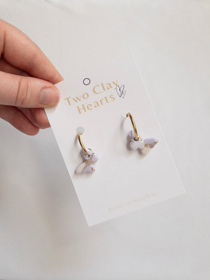 Small Purple and White Butterfly charms with gold flecks, hanging on gold hoops.