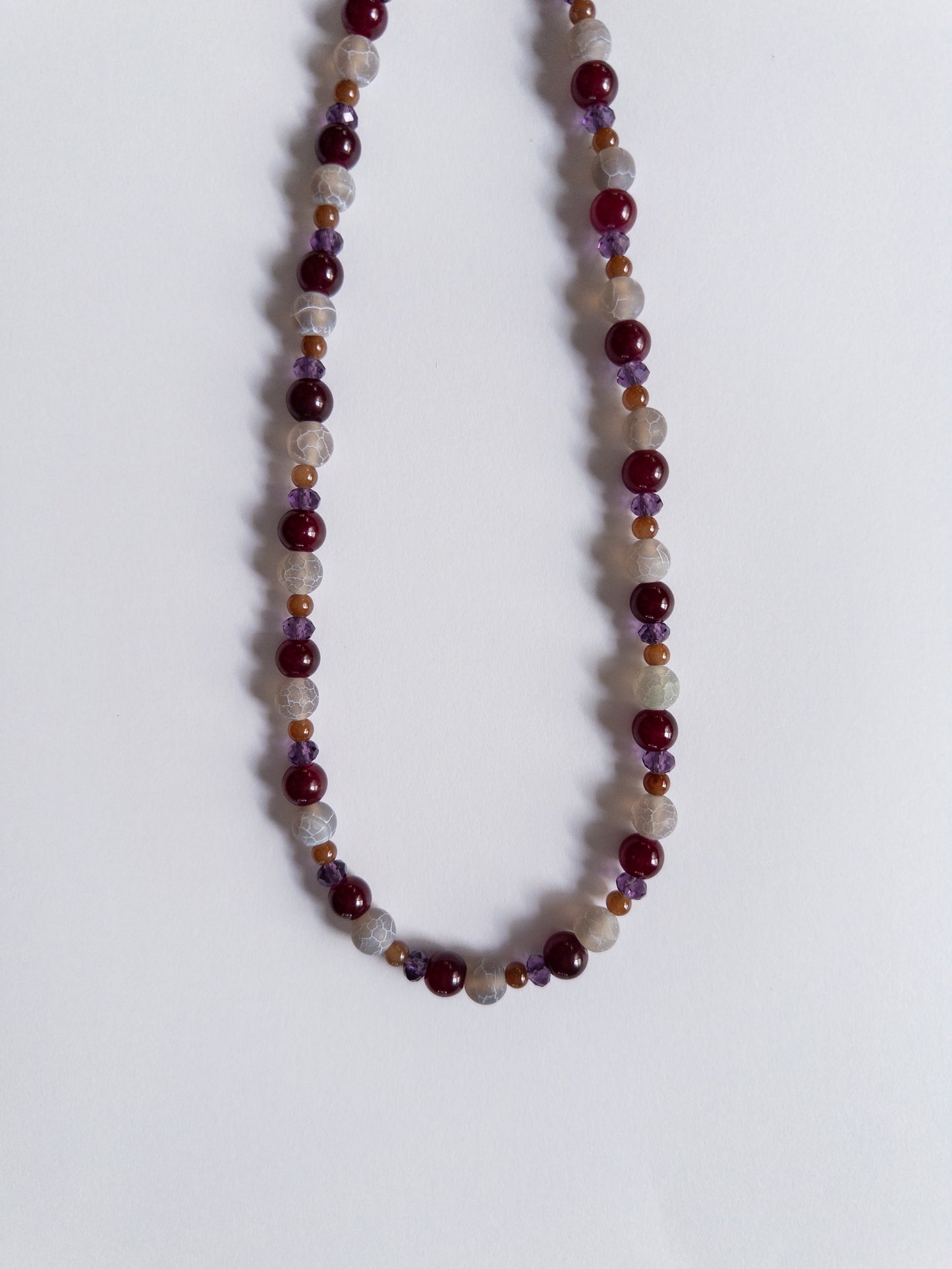 dark purple and magenta beaded necklace on white background