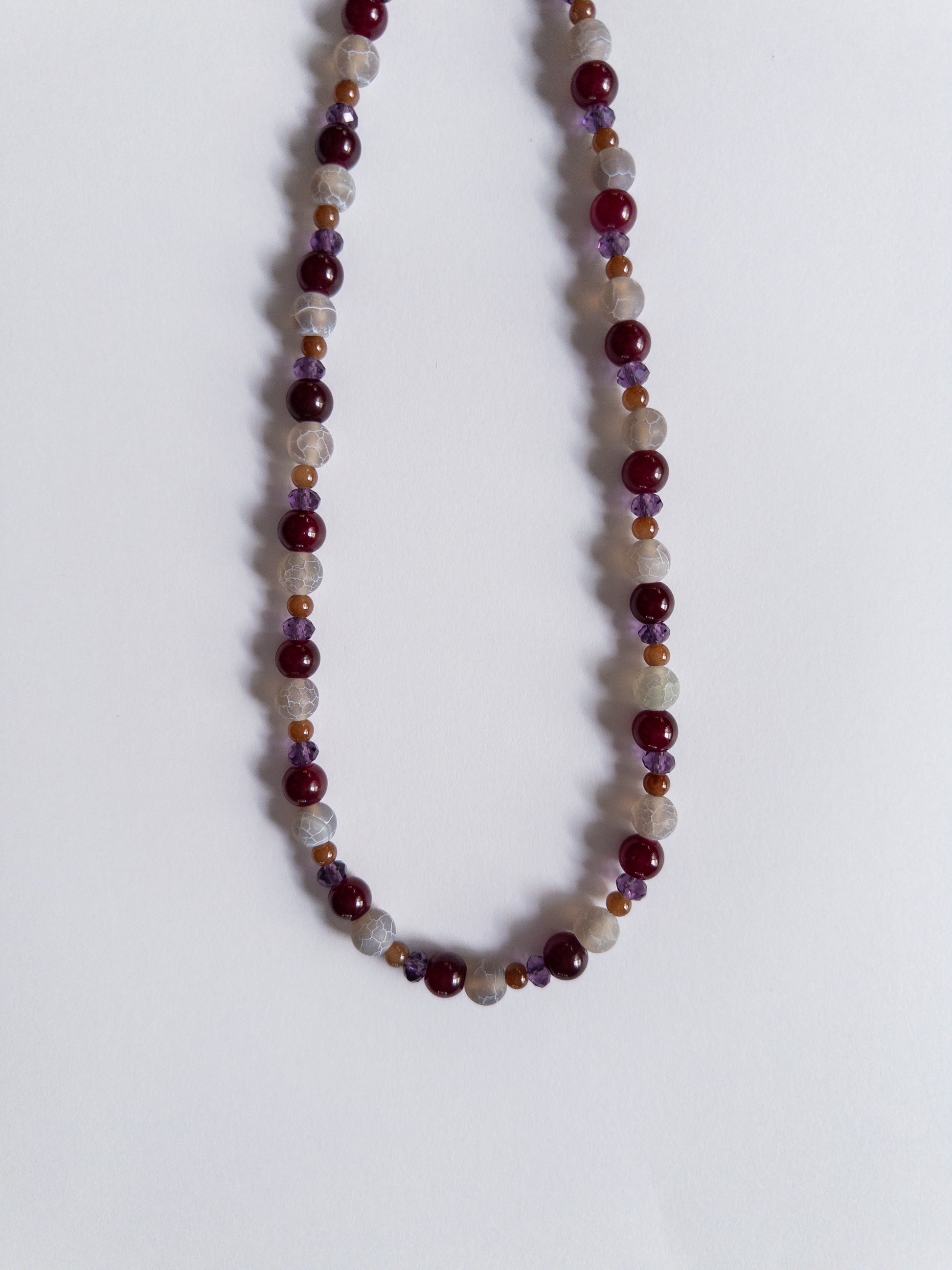 dark purple and magenta beaded necklace on white background