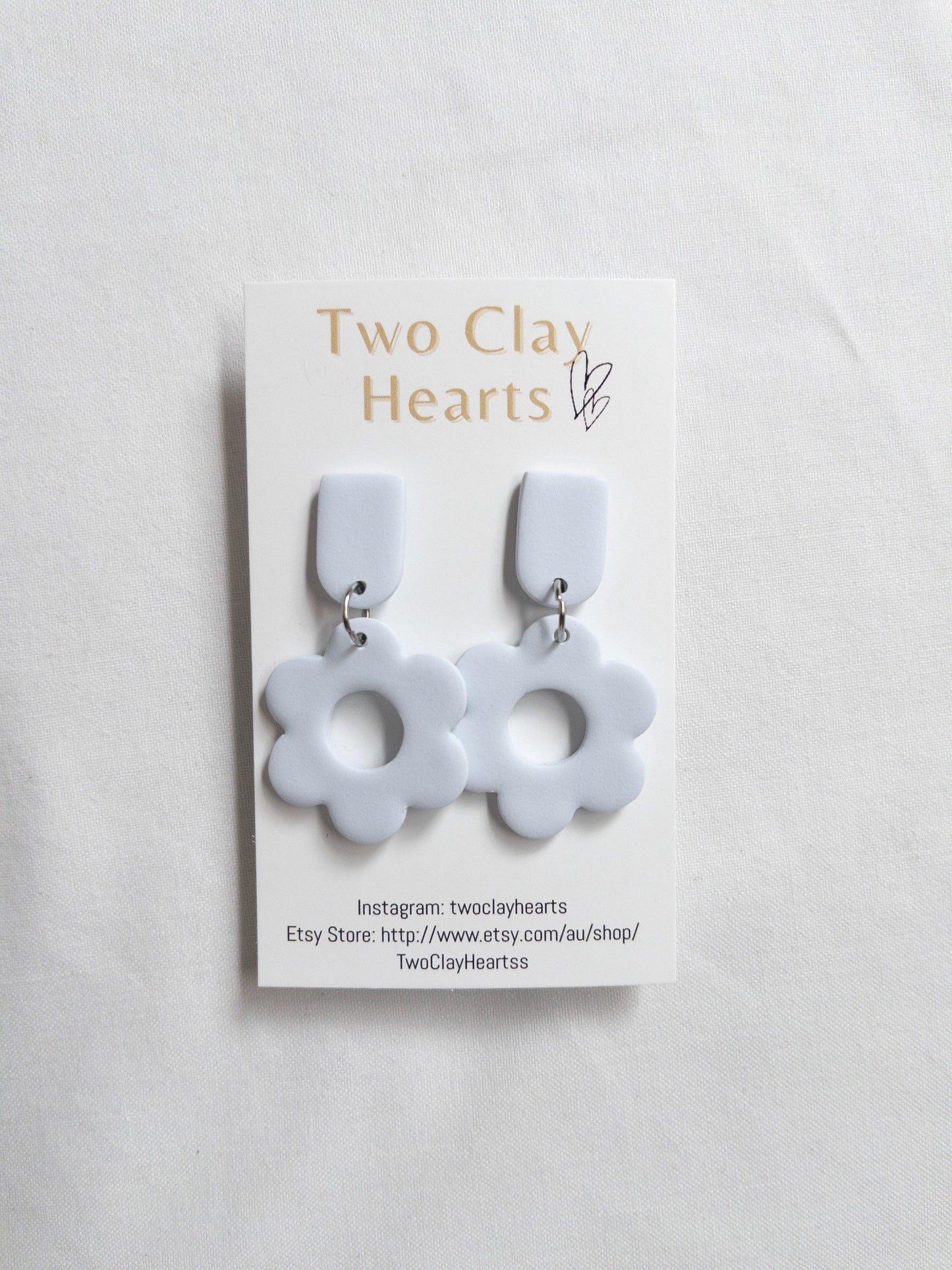 a pair of blue flower shaped dangles on a white clothe background