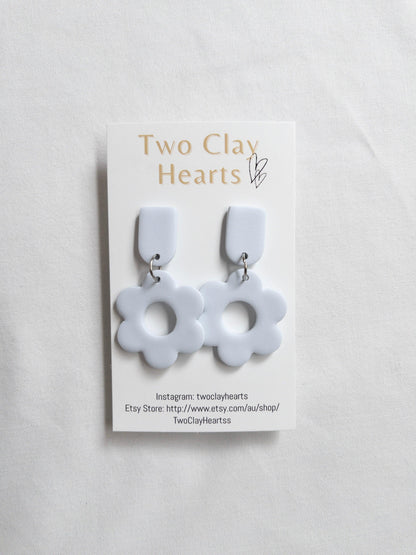 a pair of blue flower shaped dangles on a white clothe background