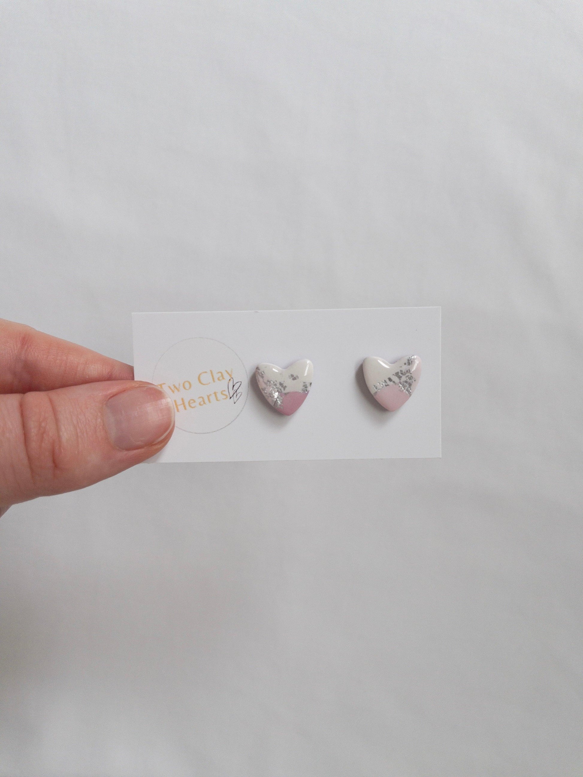 Pink and silver heart shaped stud earrings on white backing card