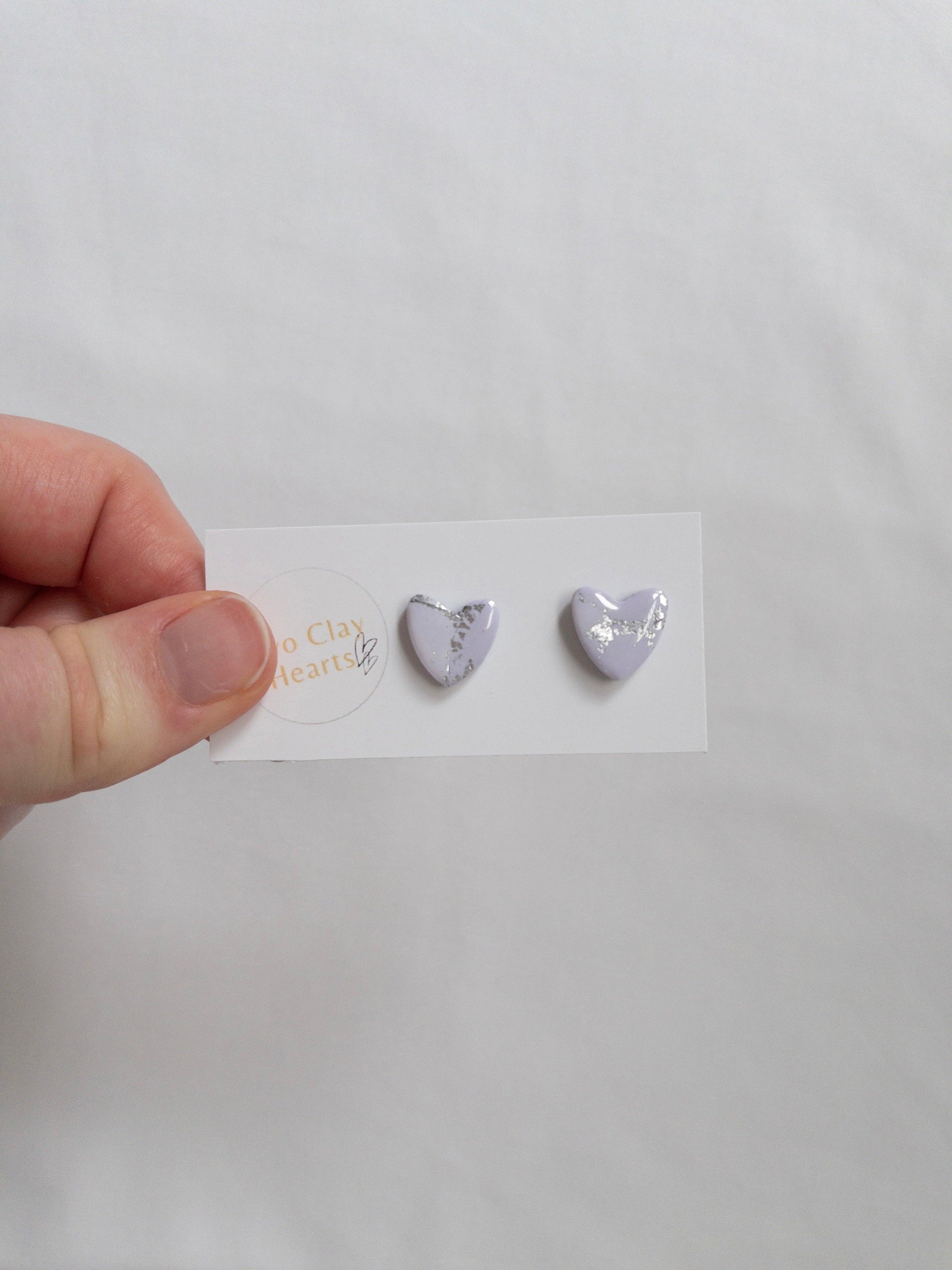 Purple and silver heart shaped stud earrings on white backing card