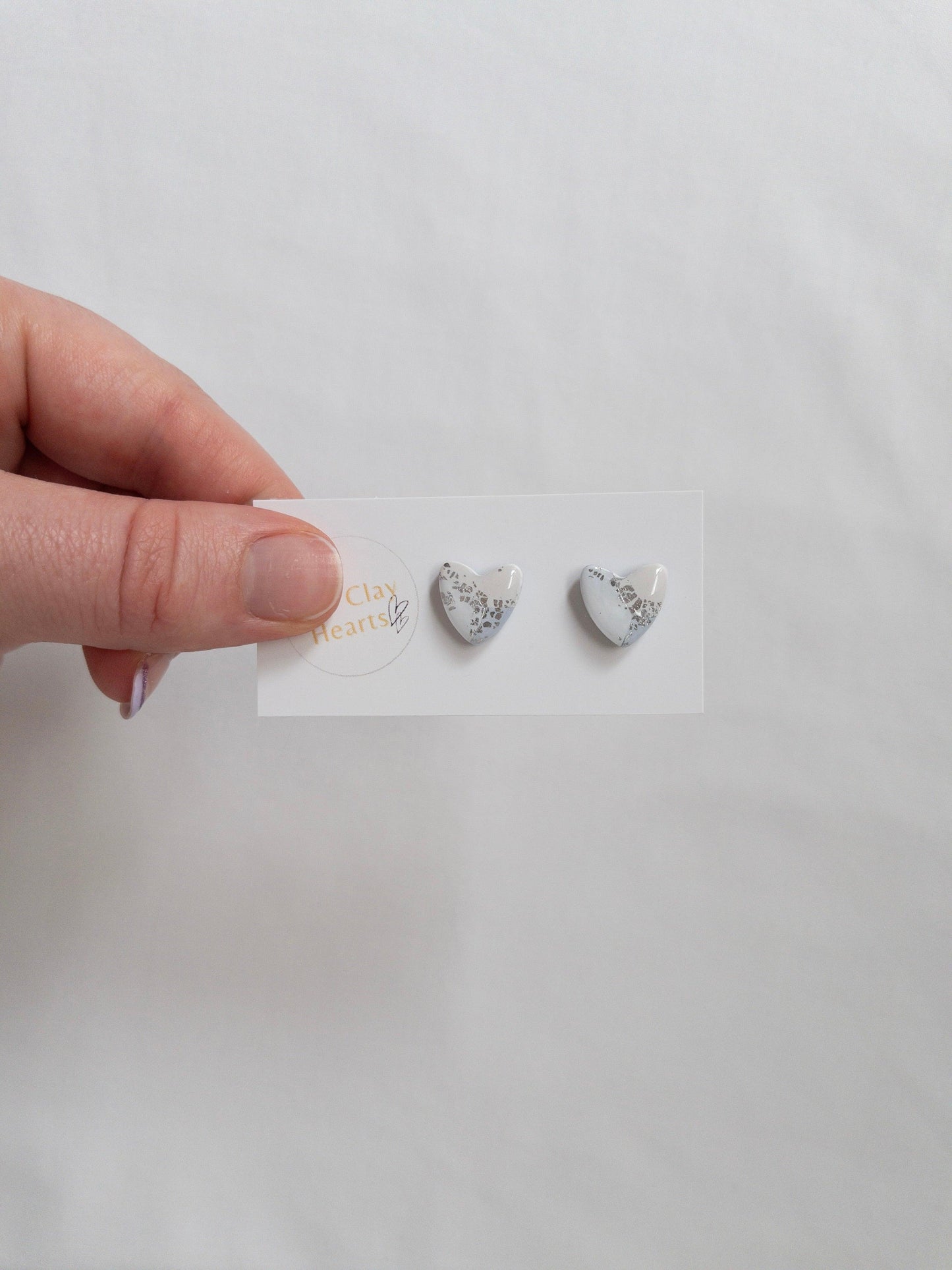 Blue and silver heart shaped stud earrings on white backing card