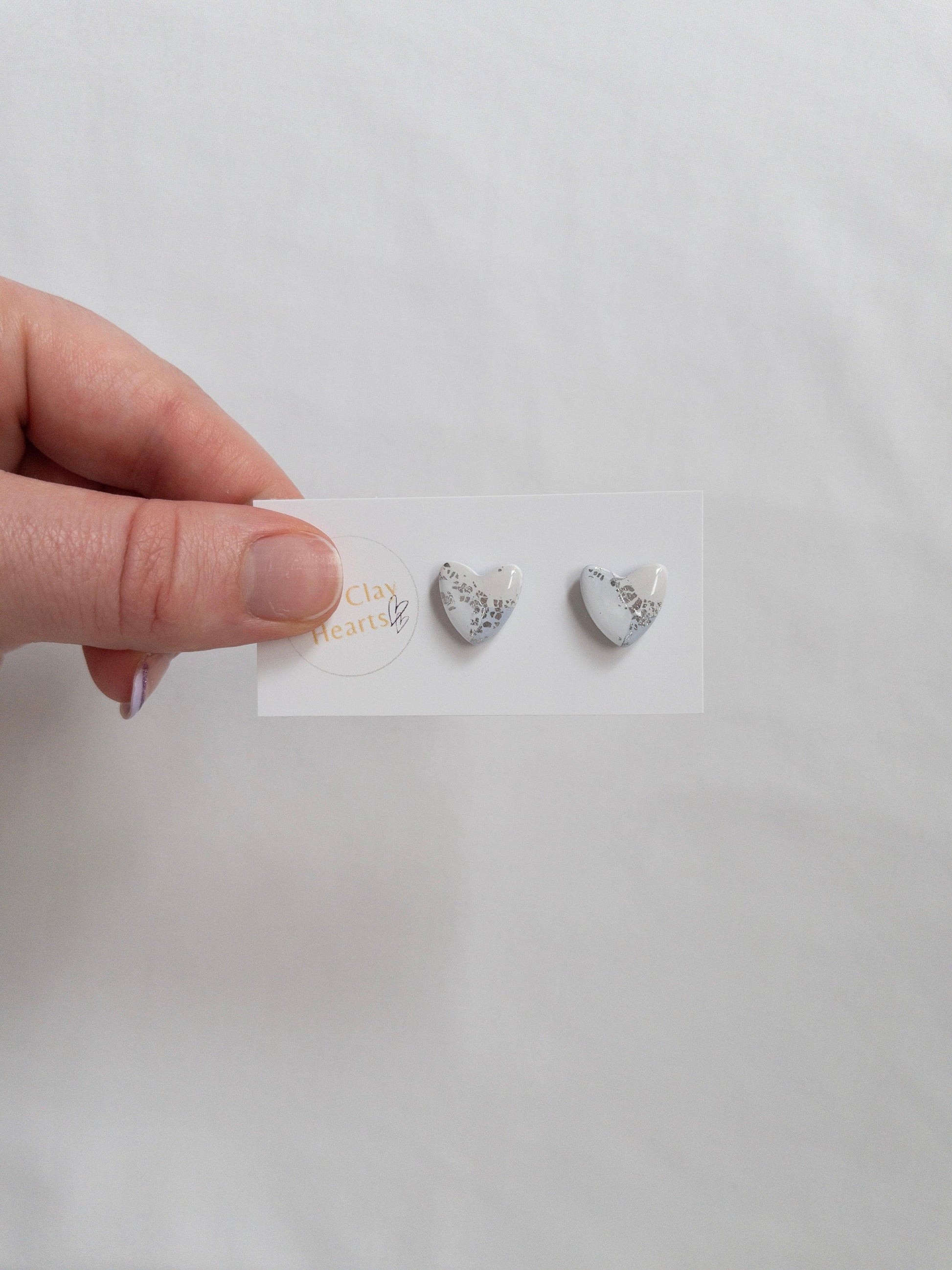 Blue and silver heart shaped stud earrings on white backing card