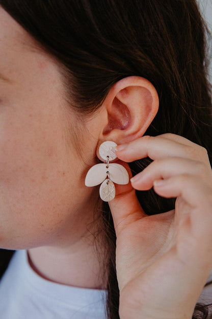 Simple cream firefly shaped earring on models ears