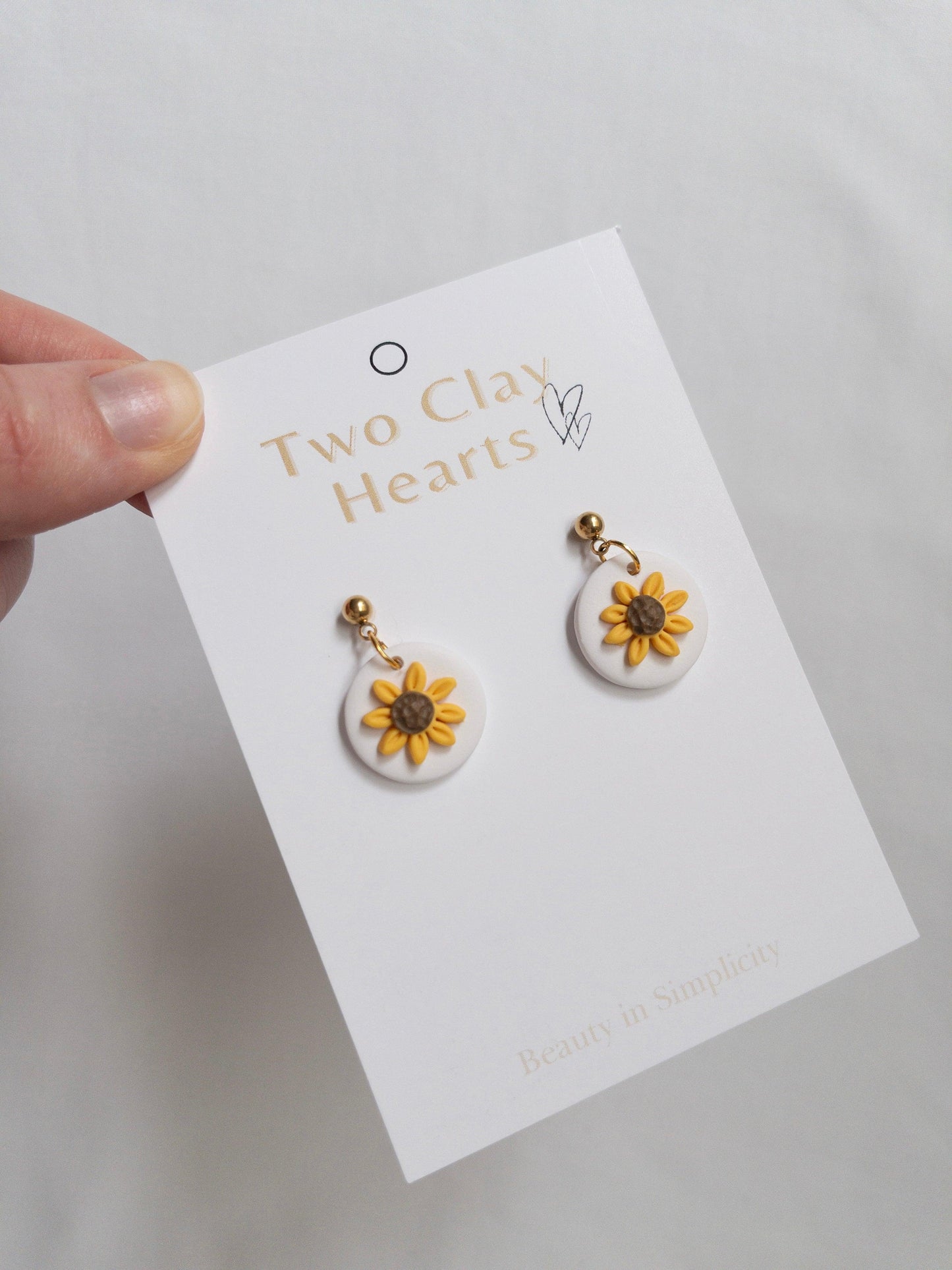 Small sunflower dangle earrings with gold ball top on white backing card