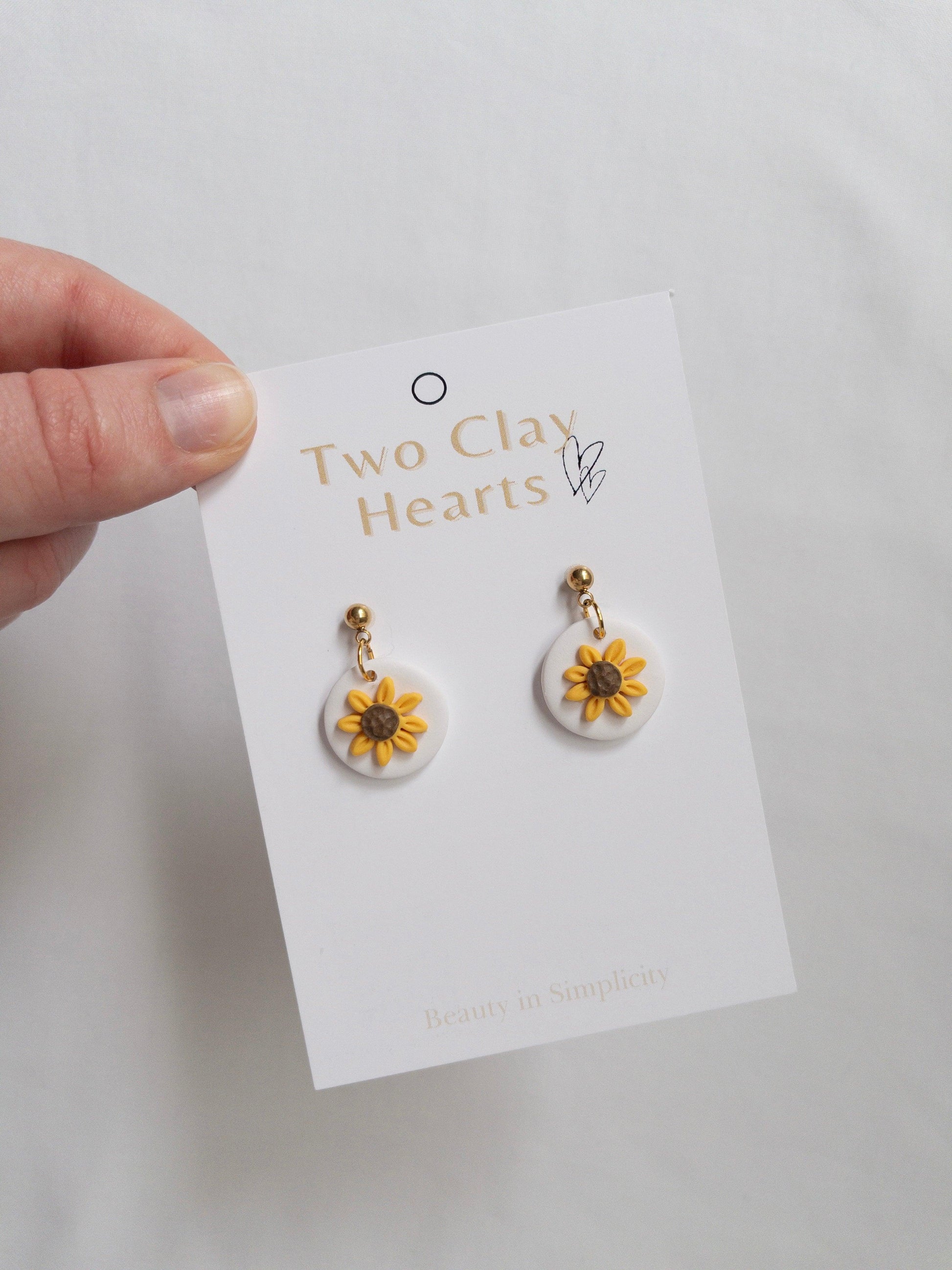 Small sunflower dangle earrings with gold ball top on white backing card