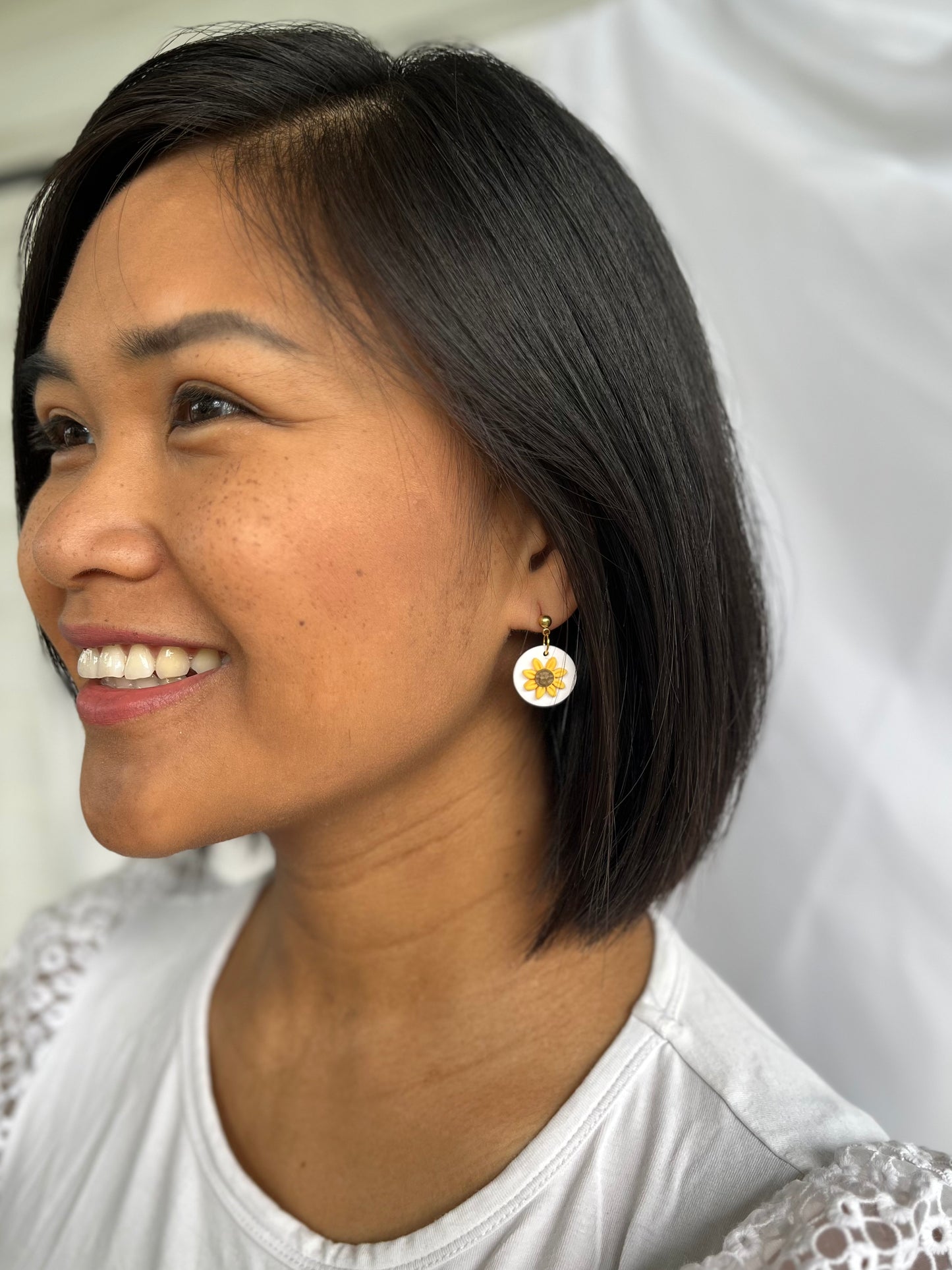 Small sunflower dangle earrings with gold ball top on model