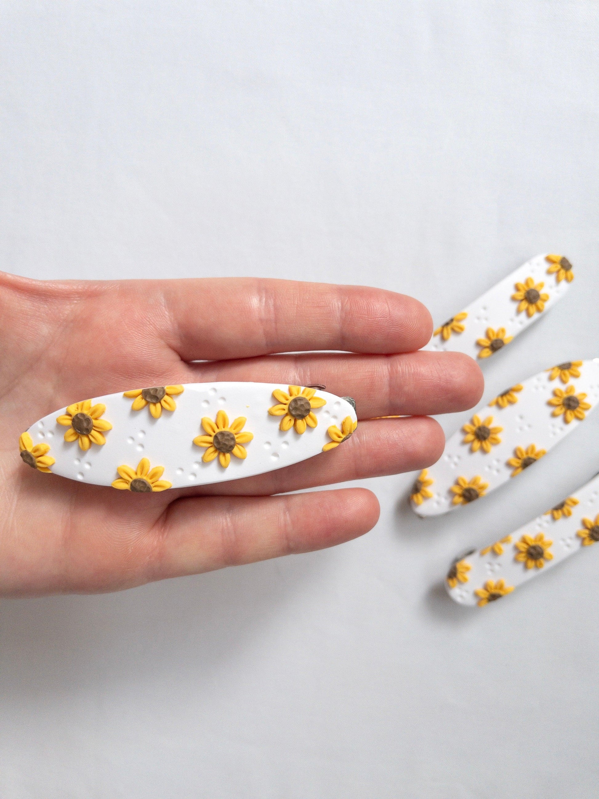 Oval sunflower hair barrette in models hand