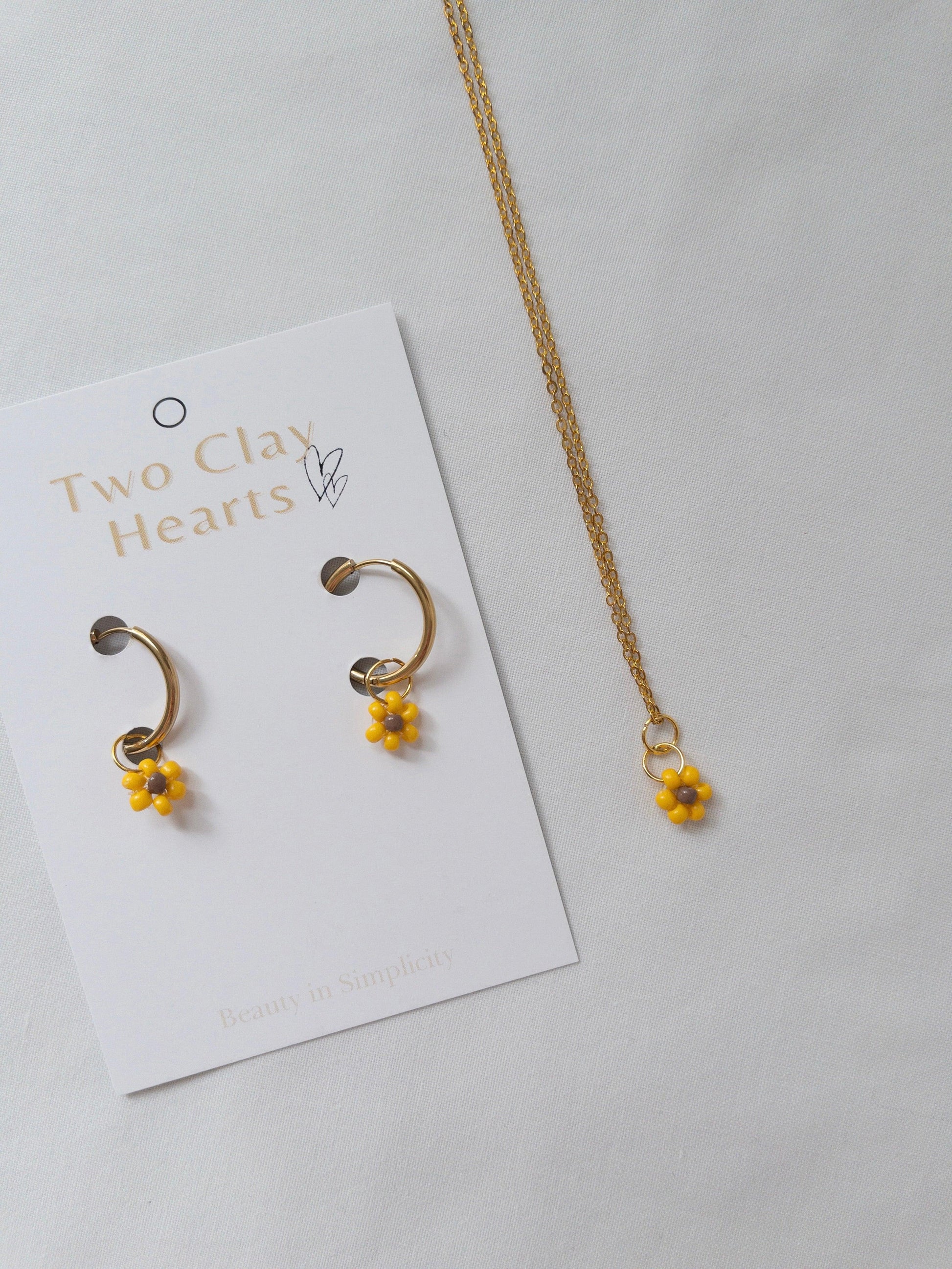 Gold and beaded sunflower necklace and hoops on white background