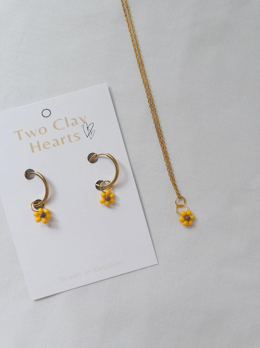 Gold and beaded sunflower necklace and hoops on white background