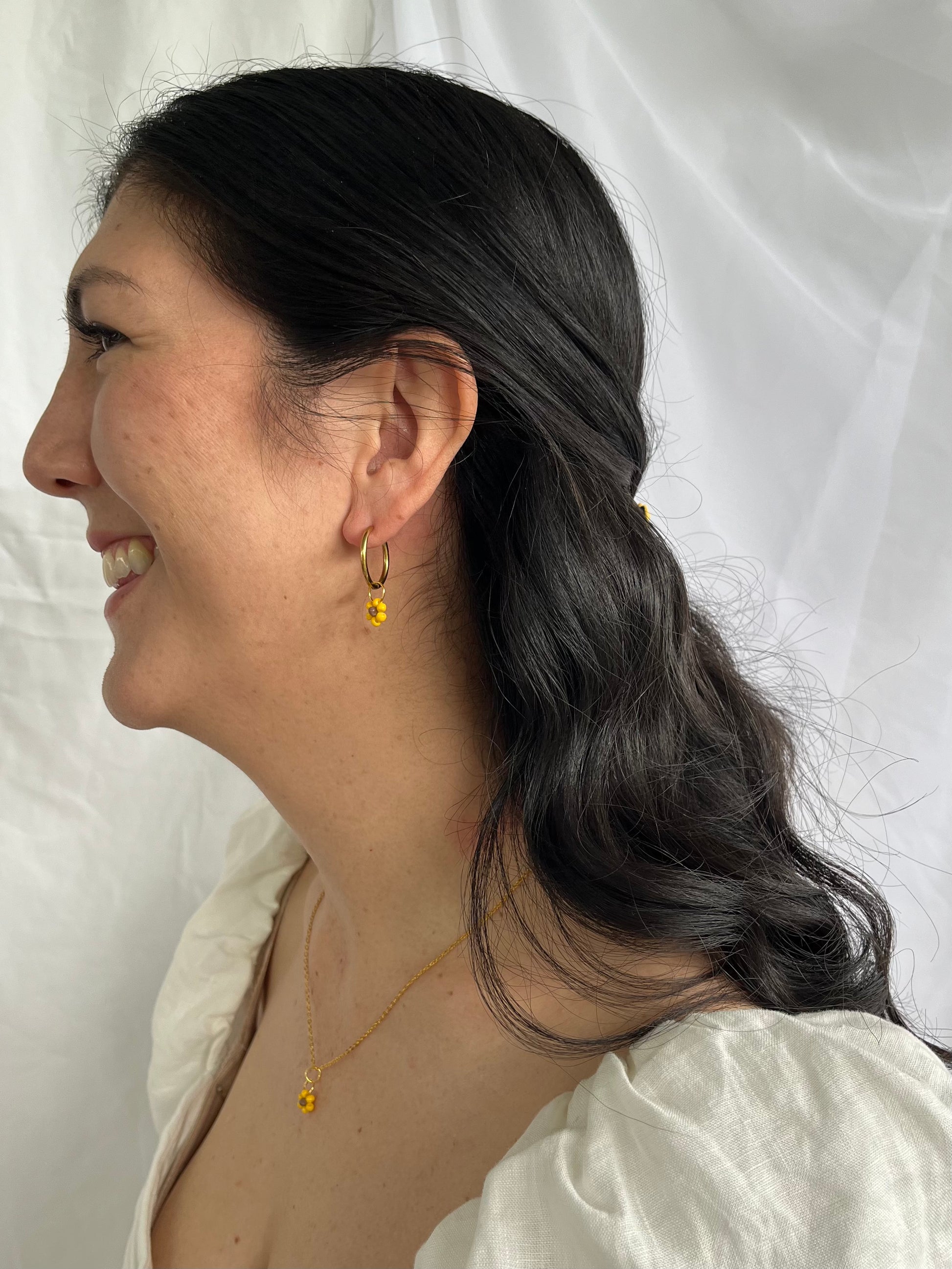 Gold and beaded sunflower necklace and hoops on model