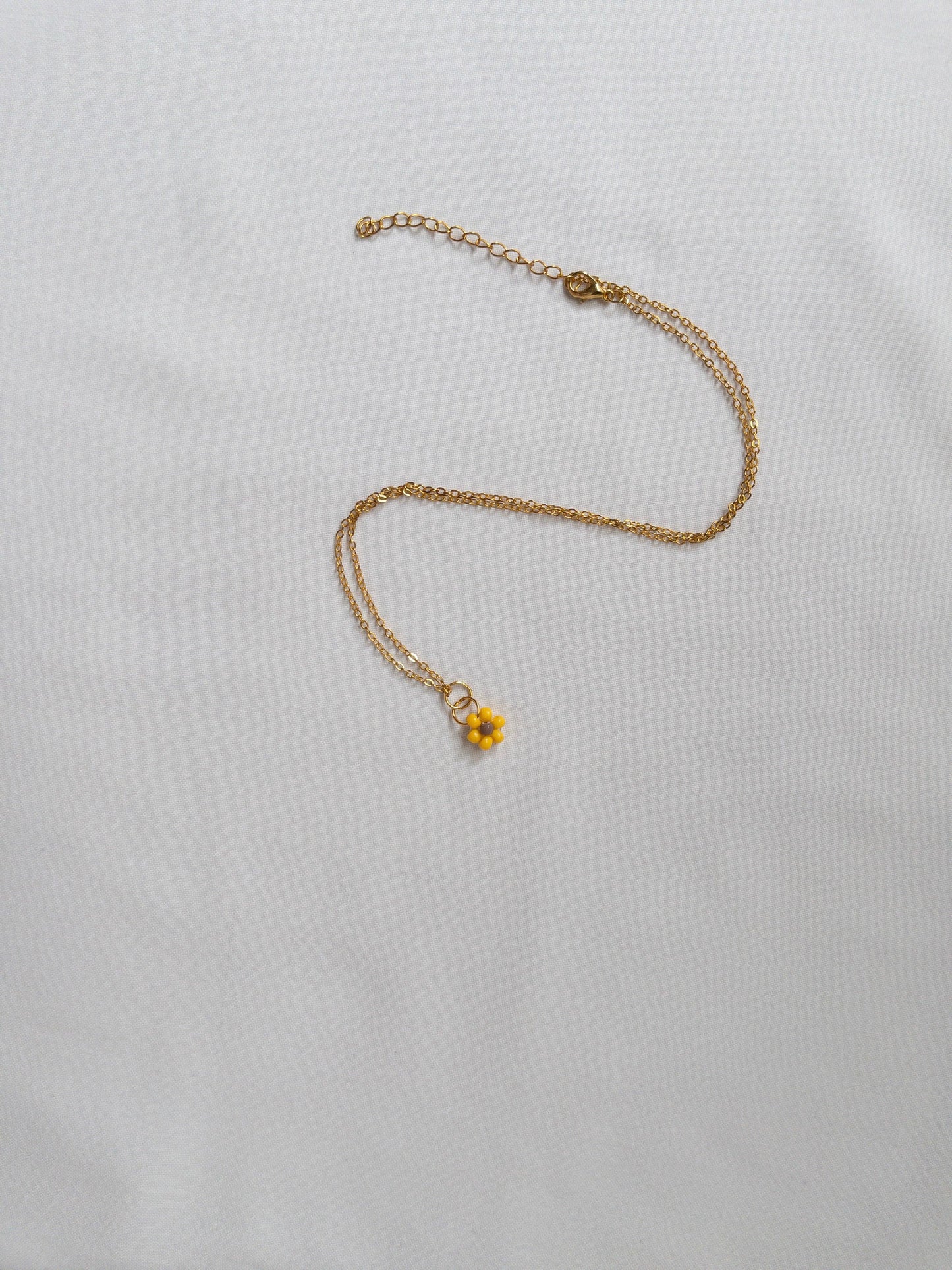 Gold and beaded sunflower necklace on white background