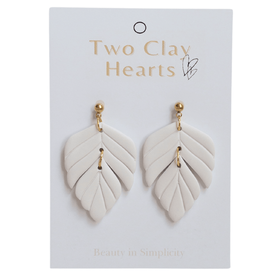 Close up on white polymer clay statement earrings on white backing card