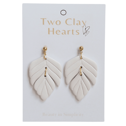 Close up on white polymer clay statement earrings on white backing card